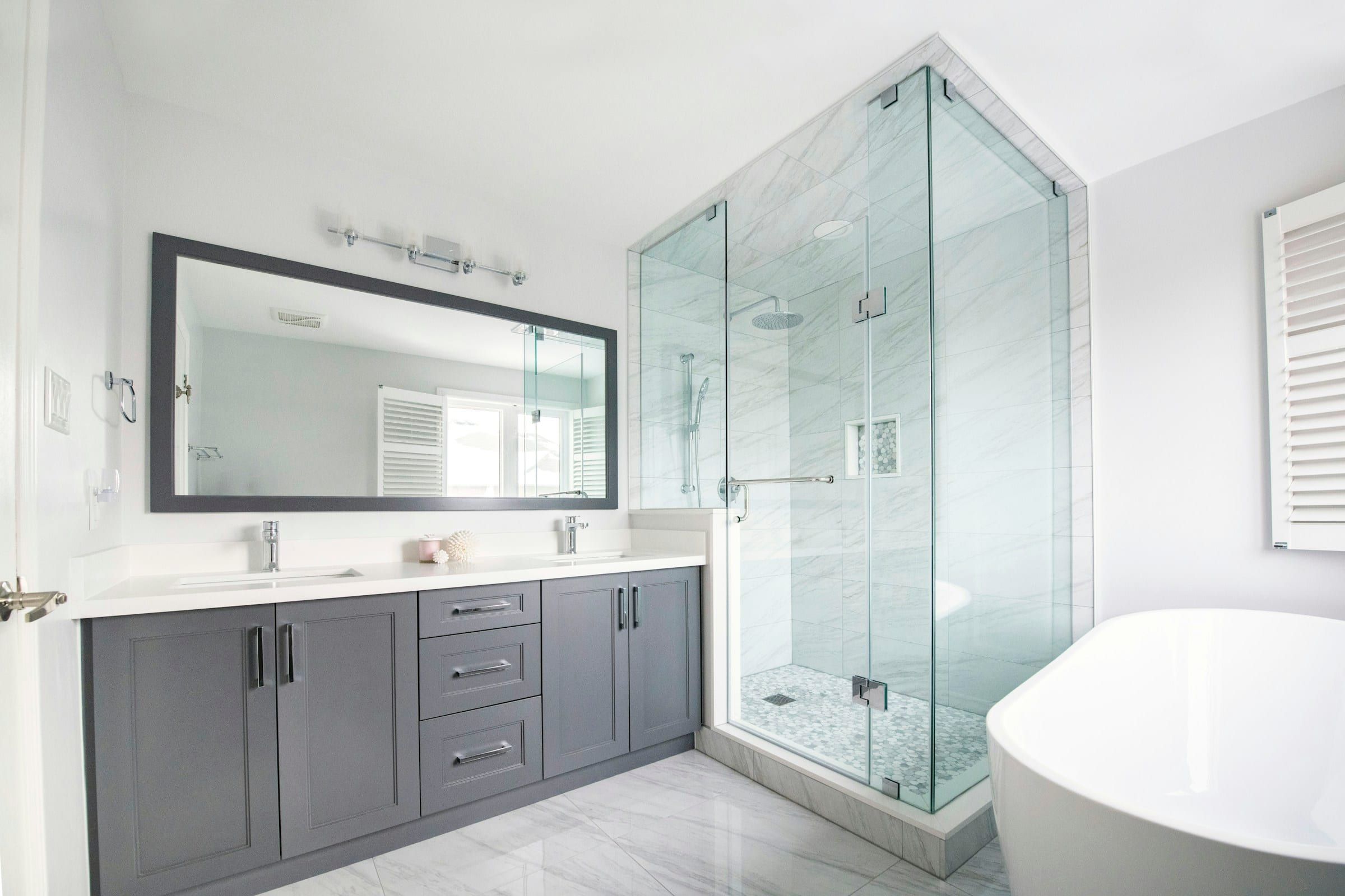 Remodeled bathroom with a glass walk-in shower, a double vanity and a freestanding tub