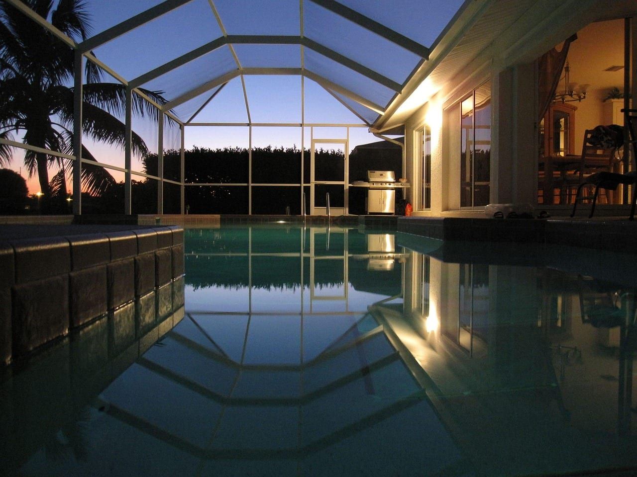 Screened pool and lanai at dusk with the house lights on