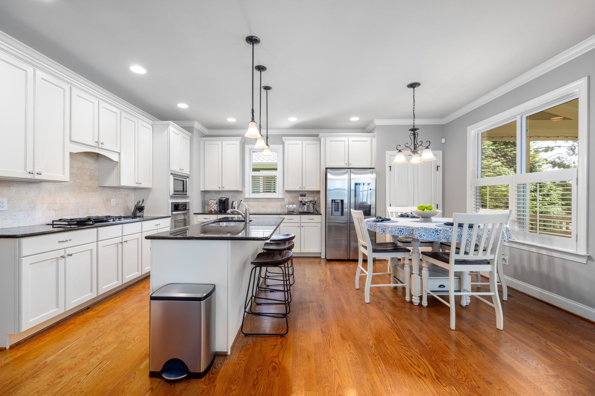 Open kitchen and dining area with white cabinets, an island and wood floors