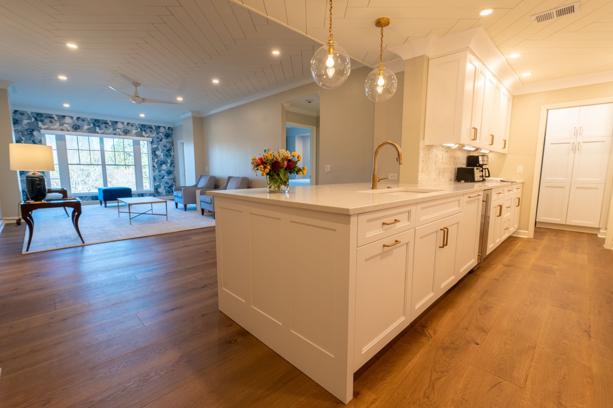 Remodeled white kitchen with a quartz island and pendant lights, open to the living room