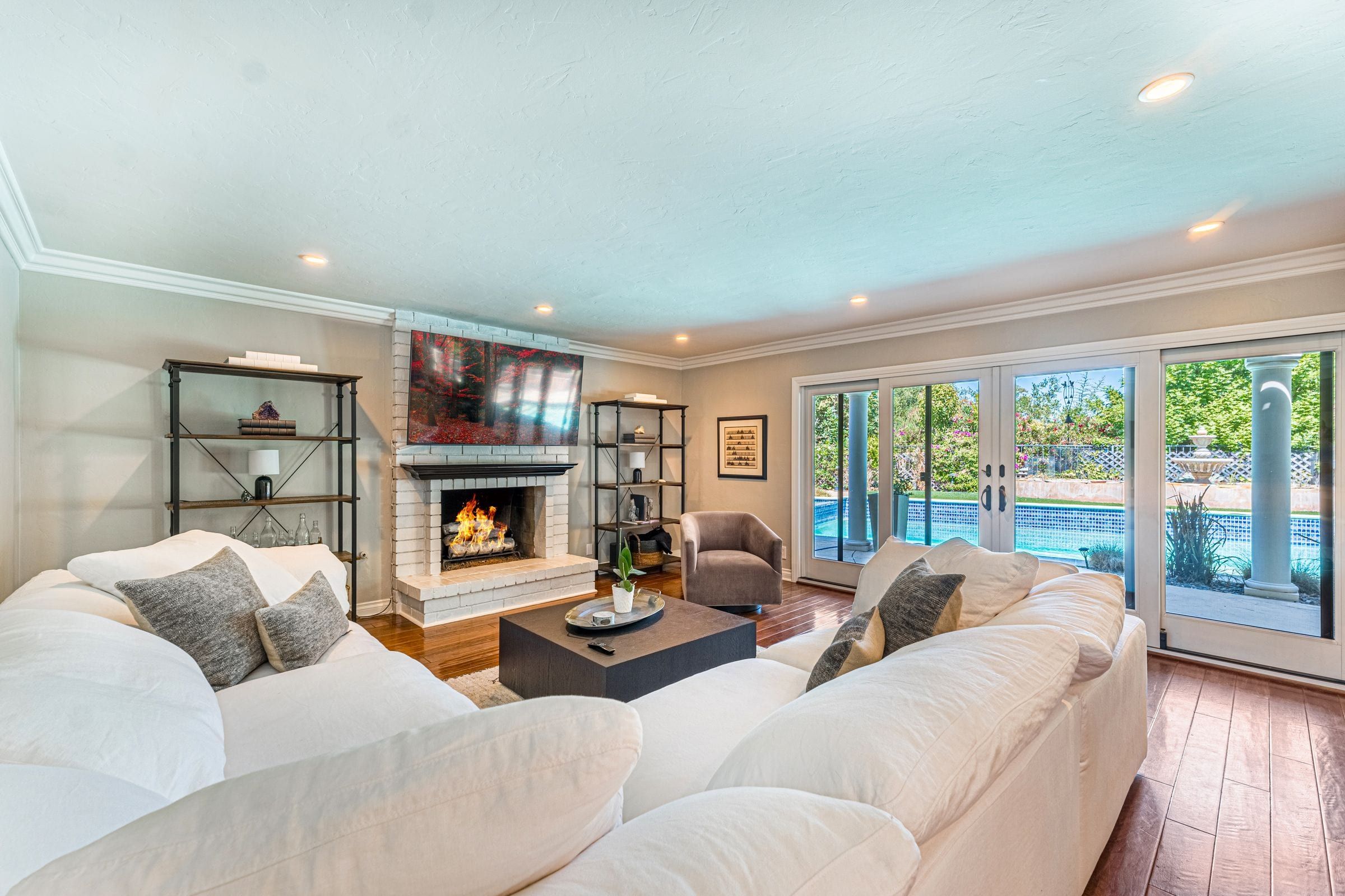 Open living room with a fireplace and French doors to the pool deck