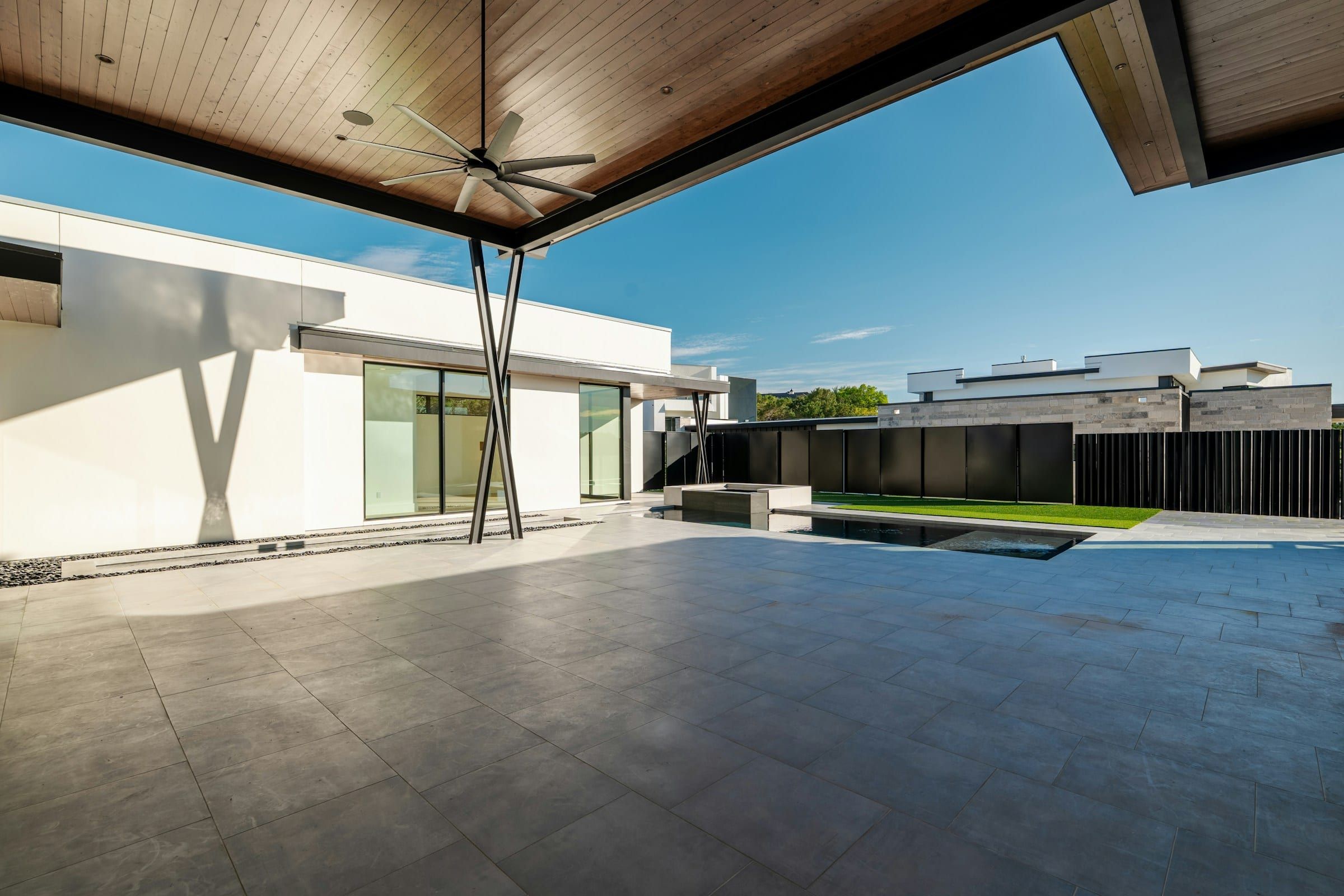 Covered patio with a ceiling fan opening to the pool deck