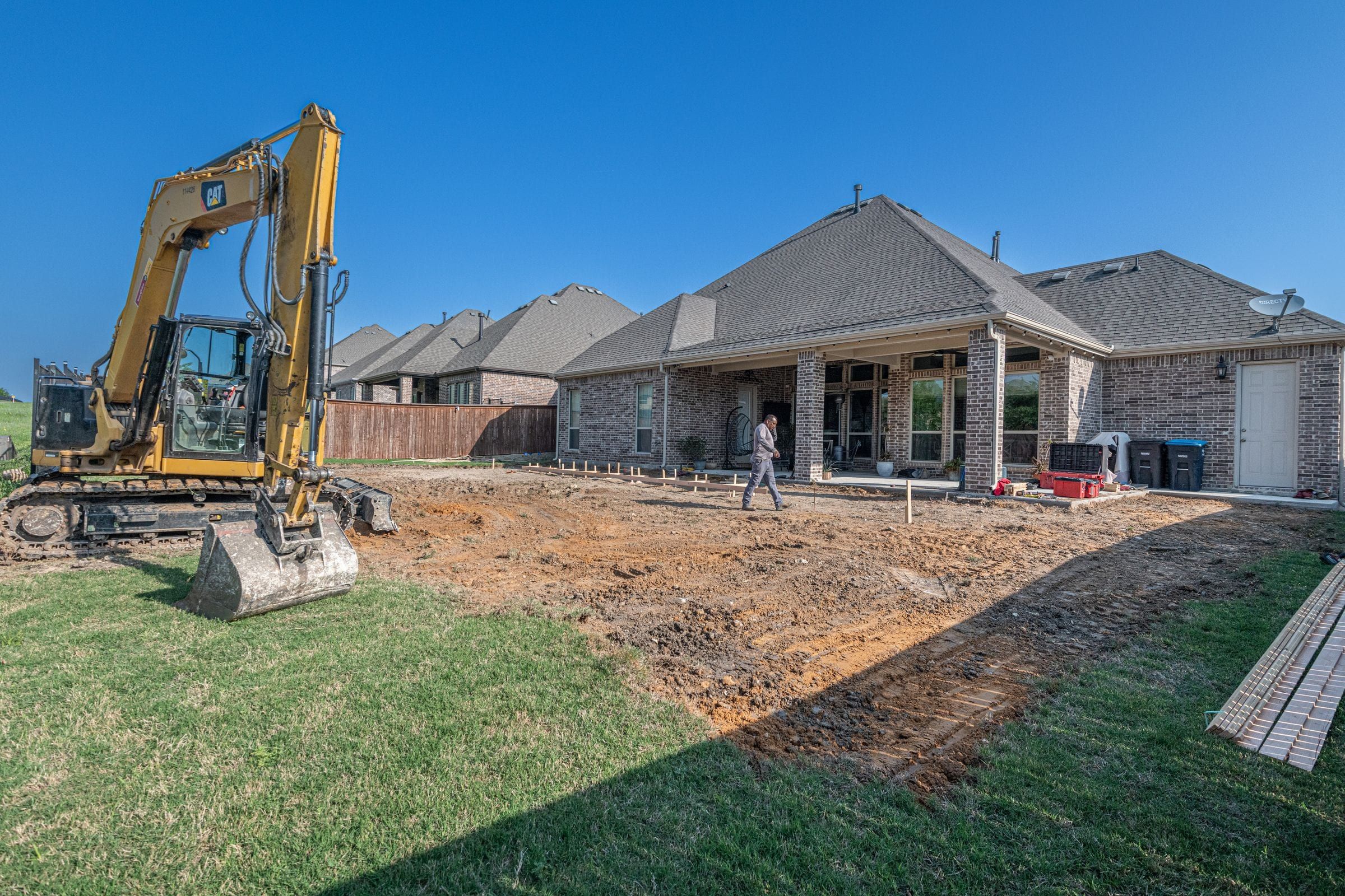 Excavator digging in the backyard of a new single-story home
