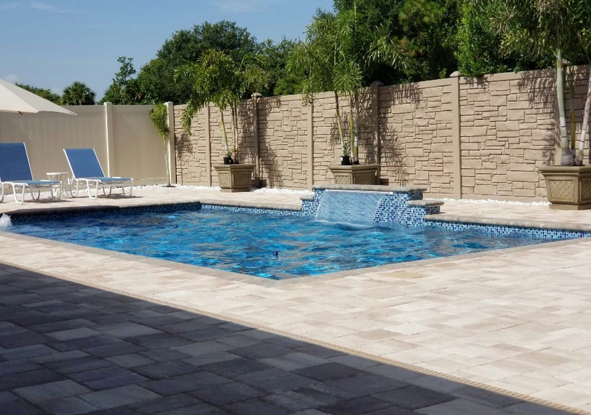 Renovated pool with a sheer descent water feature, mosaic tile and a travertine paver deck