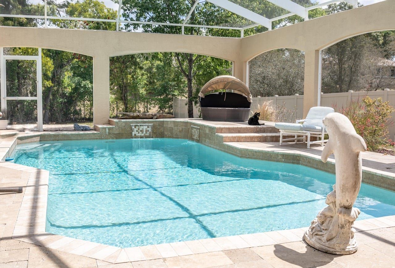 Pool and raised spa with a travertine deck by day