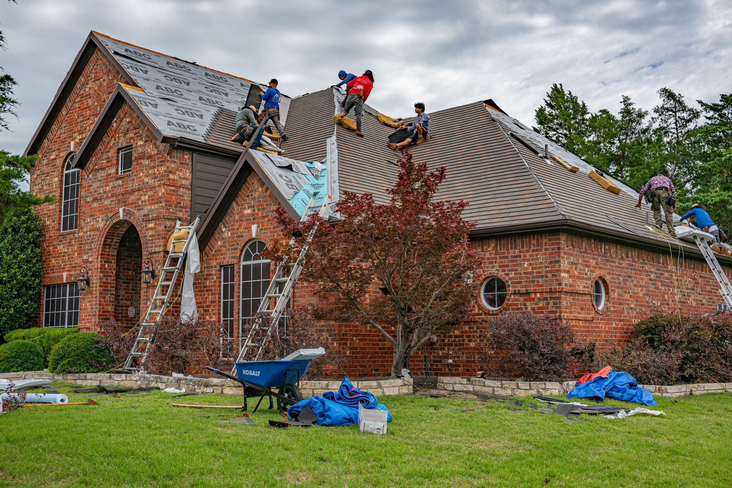 Roofing crew replacing the roof of a brick home